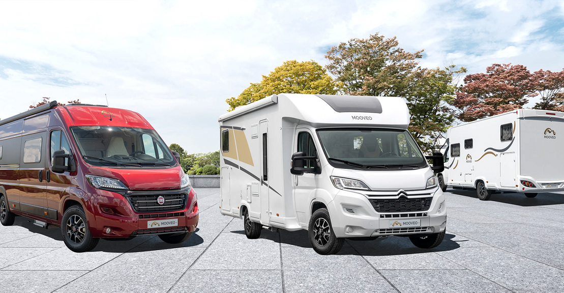 Ein rotes und ein weißes Wohnmobil von Mooveo auf einem Parkplatz